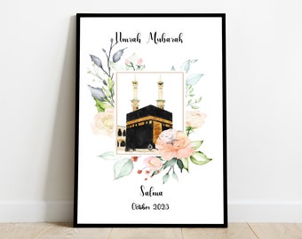 Op de afbeelding: Een witte printbare poster met een bloemenontwerp en een afbeelding van de Kaaba in Mekka. De tekst "Umrah Mubarak" staat bovenaan de poster en de tekst "Salma Oktober 2023" staat onderaan.