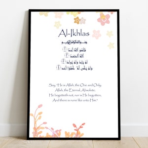 May include: A printable Islamic art print with a black frame and a white background. The print features the Arabic text of the Al-Ikhlas Surah, also known as the Purity Chapter, from the Quran. The text is in blue and is surrounded by a floral design in shades of pink, orange, and yellow. The English translation of the Surah is printed below the Arabic text.