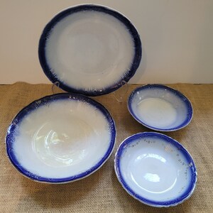 May include: Set of four blue and white ceramic bowls. The bowls have a scalloped edge and a blue and white floral design.