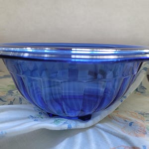 Peut inclure: Un bol en verre bleu cobalt avec un motif cannelé. Le bol a un bord légèrement évasé et une base arrondie.