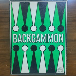 May include: A vintage Backgammon game box with a green, black, and white geometric design. The word "BACKGAMMON" is prominently displayed in white block letters. The box has a retro style.
