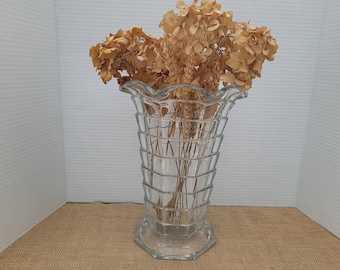 May include: A clear glass vase with a fluted design and a wide mouth. The vase is filled with dried flowers.