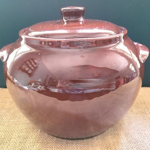 Peut inclure: Une marmite en céramique brune avec un couvercle et deux poignées. La marmite est émaillée et a une finition brillante.