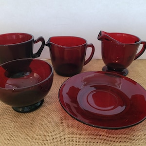 May include: Set of five ruby red glass teacups and a saucer. The cups and saucer have a vintage look.