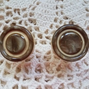 May include: Two round, brown and white, decorative knobs with a raised, concentric circle design.