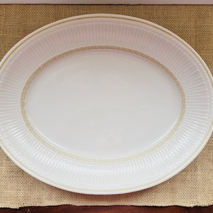May include: White oval serving platter with a gold Greek key design around the edge.