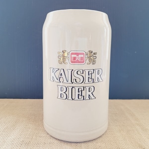 May include: White ceramic beer stein with a gold and red logo that says "Kaiser Bier".