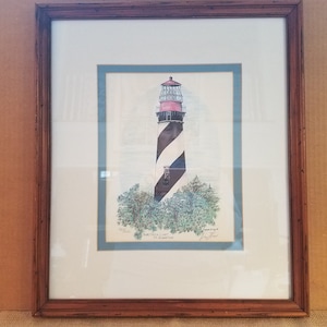 Könnte beinhalten: Gerahmter Druck eines schwarz-weiß gestreiften Leuchtturms mit rotem Dach, umgeben von grünen Bäumen. Der Druck trägt den Titel "Amelia Light, St. Augustine, Florida" und ist vom Künstler signiert.