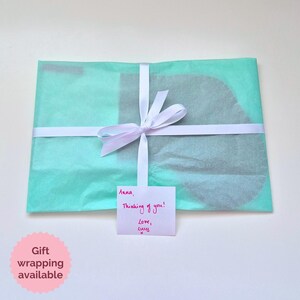 May include: A light blue gift bag with a white ribbon and a handwritten note that says "Anna, Thinking of you! Love, Lucy".