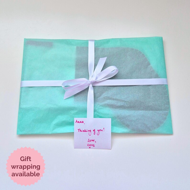 May include: A light blue gift bag with a white ribbon and a handwritten note that says "Anna, Thinking of you! Love, Lucy".