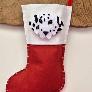 May include: Red felt Christmas stocking with a white felt cuff and a felt Dalmatian dog face appliqu&eacute;.