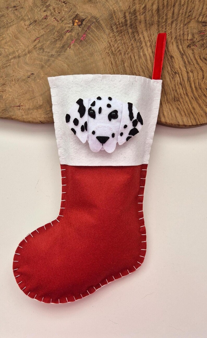 May include: Red felt Christmas stocking with a white felt cuff and a felt Dalmatian dog face appliqu&eacute;.