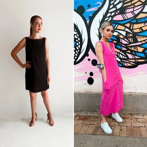 May include: Two women wearing dresses. The woman on the left is wearing a black sleeveless dress. The woman on the right is wearing a pink sleeveless dress with buttons down the front.
