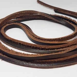 Könnte beinhalten: Zwei Stränge braunes Lederband, ein dunkelbraunes und ein hellbraunes, sind miteinander verdreht. Die Bänder sind weich und geschmeidig und haben eine leicht raue Textur.