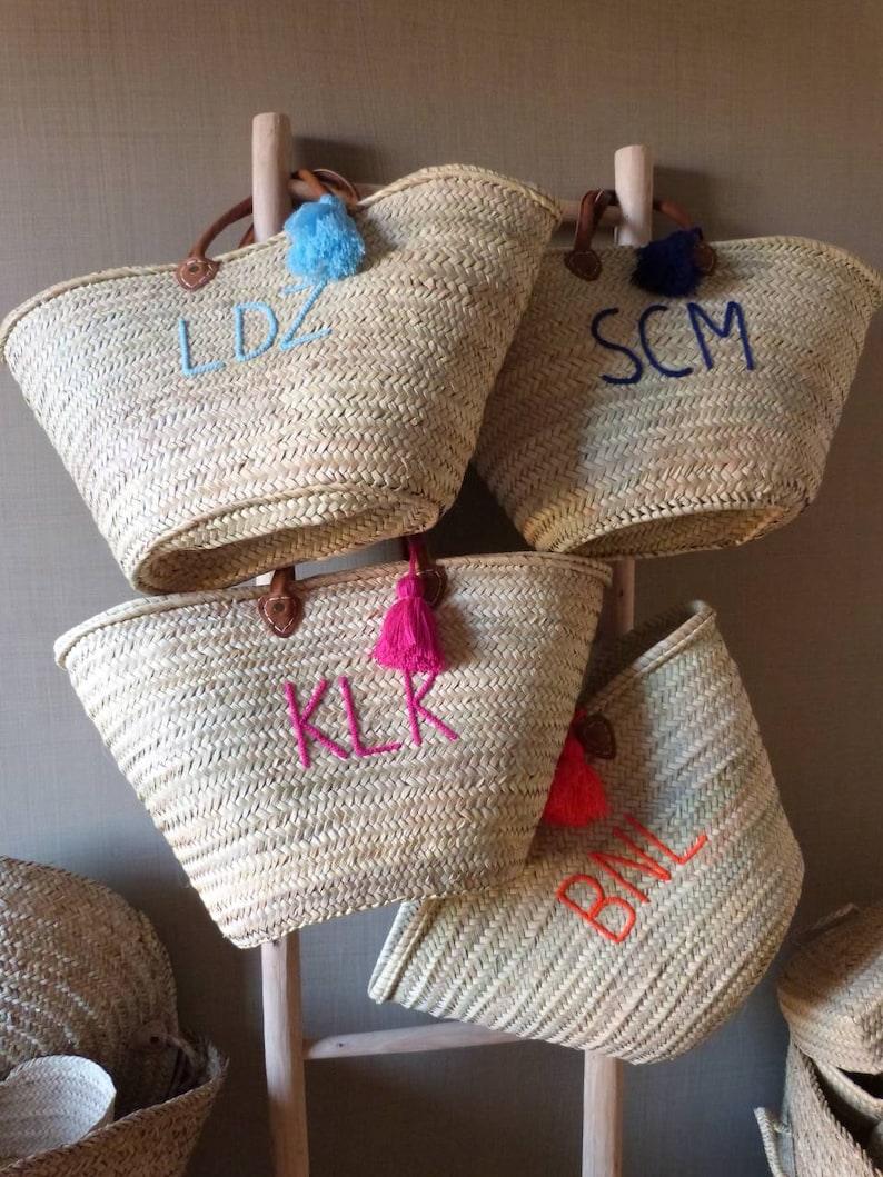 May include: Four straw tote bags with leather handles and colorful tassels. Each bag is personalized with embroidered initials: LDZ, SCM, KLK, and BML.