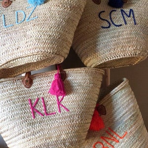 May include: Four straw tote bags with leather handles and colorful tassels. Each bag has a different set of initials embroidered on the front: LDZ, SCM, KLR, and BML.
