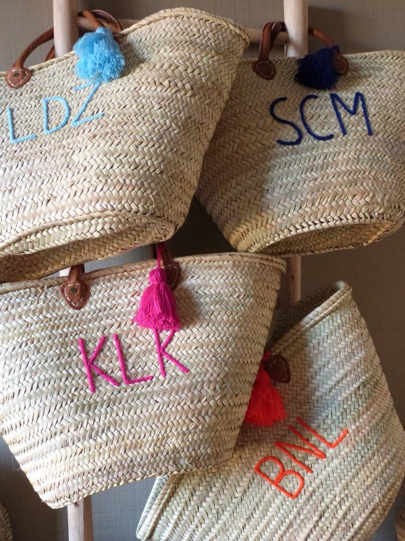 May include: Four straw tote bags with leather handles and colorful tassels. Each bag has a different set of initials embroidered on the front: LDZ, SCM, KLR, and BML.