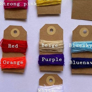 May include: A collection of yarn samples on brown card stock tags. The yarn colors include baby pink, strong pink, green, yellow, fluo, red, orange, beige, bluesky, bluenav, white, and black.