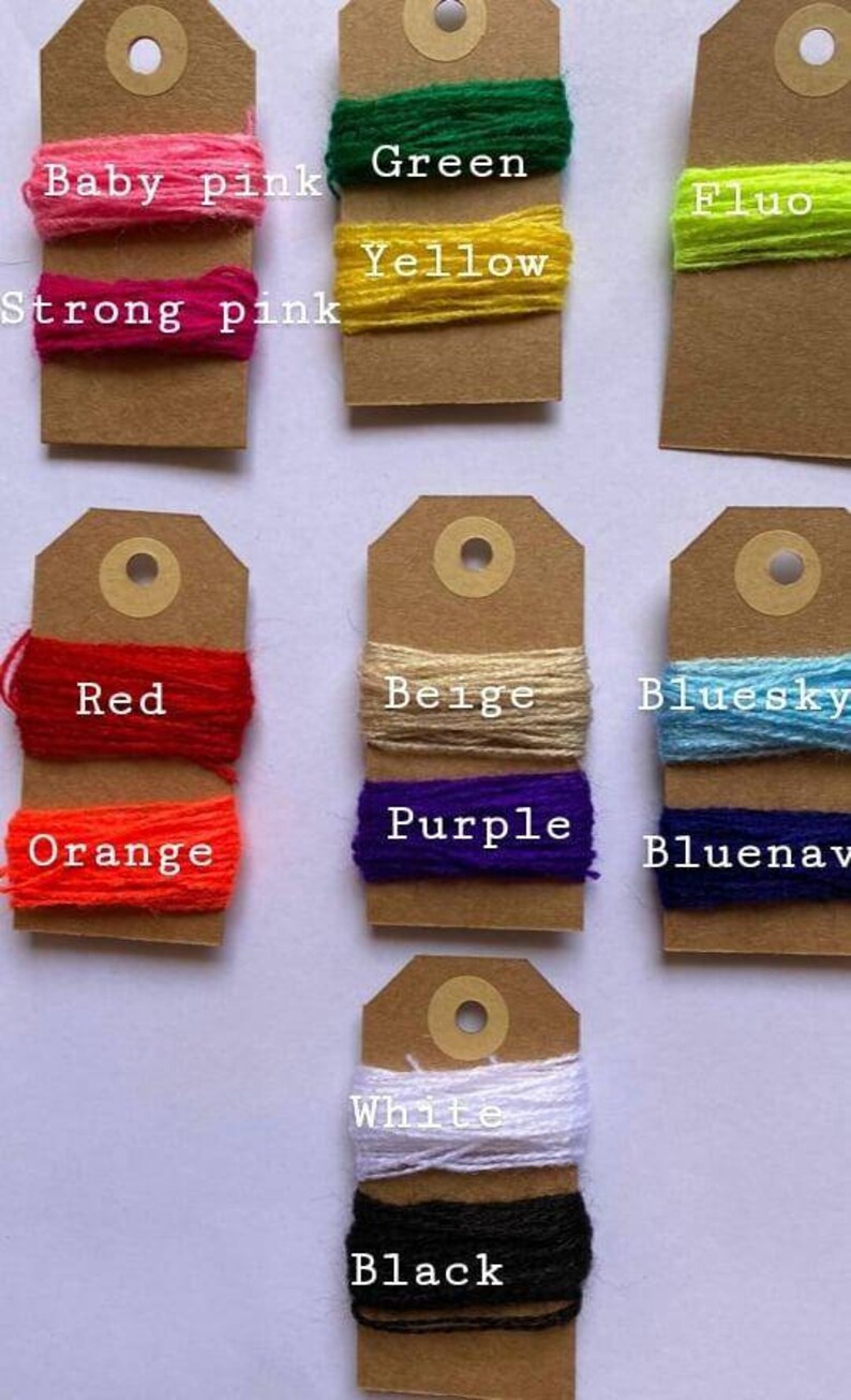May include: A collection of yarn samples on brown card stock tags. The yarn colors include baby pink, strong pink, green, yellow, fluo, red, orange, beige, bluesky, bluenav, white, and black.