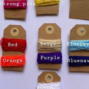 May include: A collection of yarn samples on brown card stock tags. The yarn colors include baby pink, strong pink, green, yellow, fluo, red, orange, beige, bluesky, bluenav, white, and black.