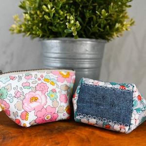 May include: Two small zippered pouches with floral patterns. One pouch is pink and white with a floral print, the other is blue and white with a floral print and a denim patch.