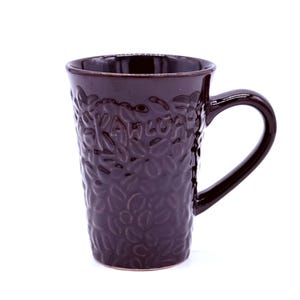 May include: A dark brown ceramic coffee mug with a textured surface featuring a pattern of coffee beans. The mug has a curved handle and the word "Kahlua" is embossed on the side. The mug is designed for hot beverages.