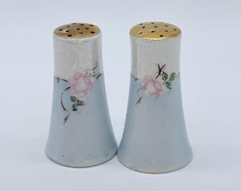 Salero y pimentero de porcelana vintage con tapa dorada y diseño floral de rosas rosas.