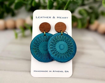 Peut inclure: Boucles d'oreilles en cuir turquoise avec un accent en bois et un motif floral. Les boucles d'oreilles sont faites à la main à Athens, en Géorgie. Leather & Heart.