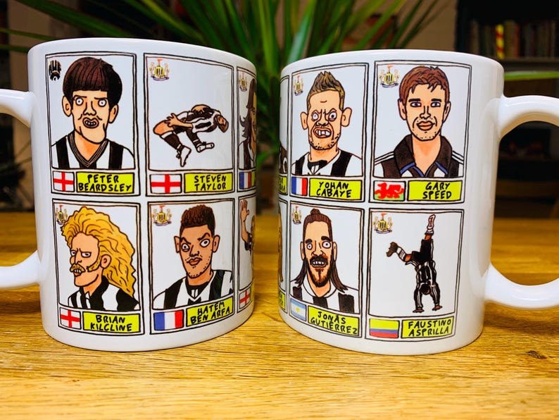 Peut inclure: Deux tasses en c&eacute;ramique blanche avec des illustrations en noir et blanc de joueurs de football. Chaque tasse pr&eacute;sente un joueur diff&eacute;rent avec son nom et son &eacute;quipe imprim&eacute;s en dessous. Les tasses sont sur une surface en bois.