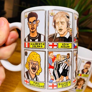 Peut inclure: Une tasse en c&eacute;ramique blanche avec une illustration de joueurs de football en dessin anim&eacute;. La tasse pr&eacute;sente quatre joueurs diff&eacute;rents, dont Nolberto Solano, Kevin Keegan, Paul Gascoigne et Bowyer & Dyer. La tasse a une poign&eacute;e noire et un int&eacute;rieur blanc.