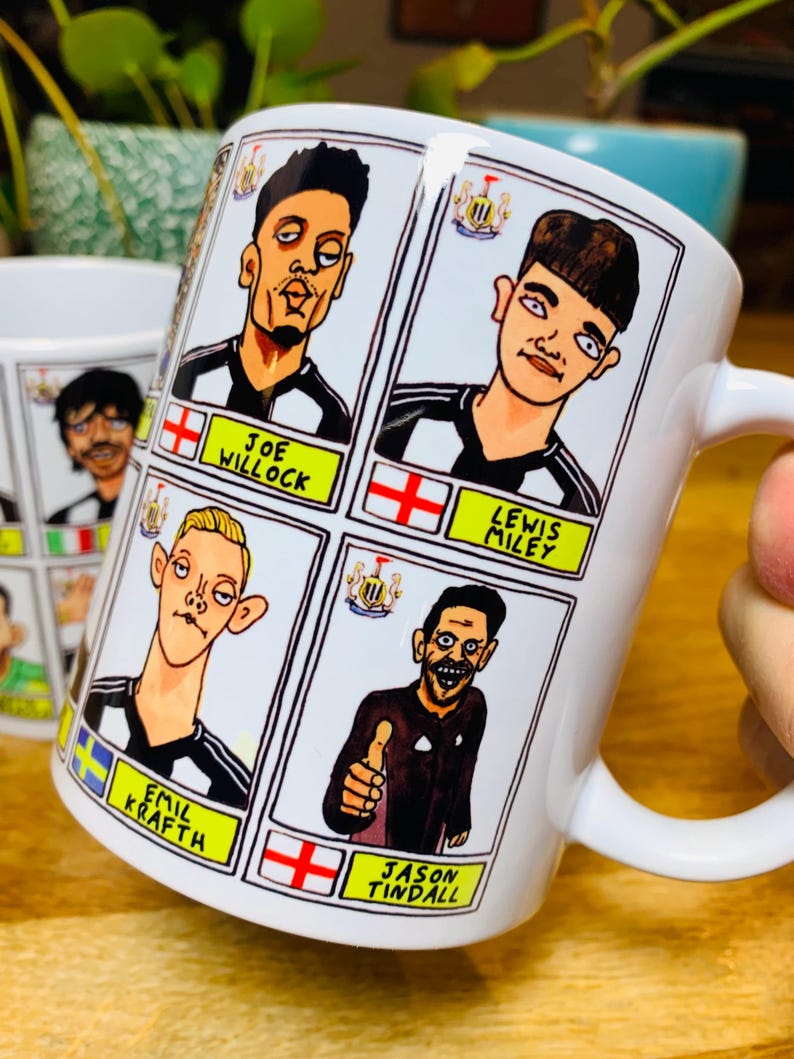 Puede incluir: Taza de cer&aacute;mica blanca con una ilustraci&oacute;n de dibujos animados de cuatro jugadores de f&uacute;tbol. La taza presenta un dise&ntilde;o de camiseta de f&uacute;tbol a rayas blancas y negras con detalles amarillos. Los nombres de los jugadores est&aacute;n impresos debajo de sus im&aacute;genes: Joe Willock, Lewis Miley, Emil Krafth y Jason Tindall.
