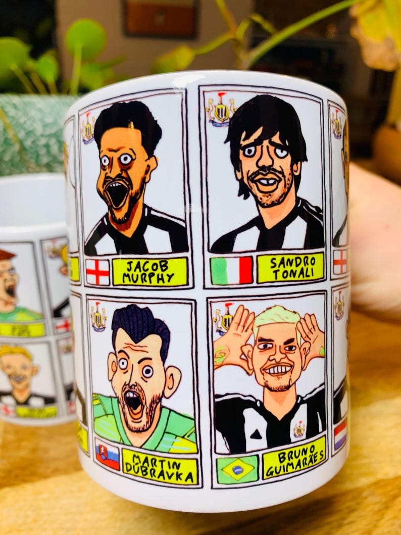 Puede incluir: Taza de cer&aacute;mica blanca con ilustraciones de dibujos animados de jugadores de f&uacute;tbol. Cada jugador lleva un uniforme de f&uacute;tbol blanco y negro y tiene una bandera que representa su pa&iacute;s de origen. El texto en la taza dice "Jacob Murphy", "Sandro Tonali", "Martin Dubravka" y "Bruno Guimaraes".