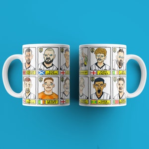 以下が含まれることがあります： 両側にサッカー選手のカラフルな漫画のイラストが描かれた白いマグカップ2つ。マグカップは、各正方形に異なる選手がいる9つの正方形のグリッドを特徴としています。選手は異なるジャージを着ており、肌の色も異なります。マグカップはサッカーファンへの素晴らしい贈り物です。