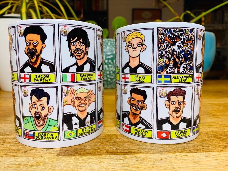 Puede incluir: Dos tazas de cer&aacute;mica blanca con ilustraciones de dibujos animados en blanco y negro de jugadores de f&uacute;tbol. Cada taza presenta un conjunto diferente de jugadores con sus nombres y nacionalidades impresos debajo de cada imagen.