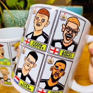 Puede incluir: Taza de cer&aacute;mica blanca con una ilustraci&oacute;n de dibujos animados en blanco y negro de jugadores de f&uacute;tbol. La taza presenta los nombres "Kieran Trippier", "Harvey Barnes", "Sven Botman" y "Jamaal Lascelles".