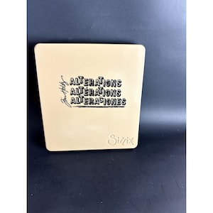 Könnte beinhalten: Eine beige quadratische Stanzschablone mit dem Text "ALTERATIONS" in schwarzer Schrift, dreimal in verschiedenen Stilen wiederholt. Der Text "Sizzix" ist ebenfalls in schwarzer Schrift in der rechten unteren Ecke gedruckt.
