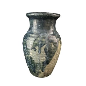 Può includere: Un vaso in ceramica con una smaltatura verde e bianca. Il vaso ha un corpo arrotondato e un collo stretto.