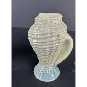 May include: A ceramic vase shaped like a seashell with a light green and blue iridescent glaze.