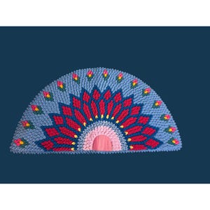May include: A semi-circular rug featuring a textured, tufted design in shades of light blue, deep red, and soft pink. The pattern radiates from a central pink semi-circle, with small floral-like accents in yellow and green scattered throughout.