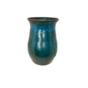 Könnte beinhalten: Eine tealblaue Keramikvase mit braunem Rand. Die Vase hat eine abgerundete, bauchige Form und eine glatte, glänzende Oberfläche.