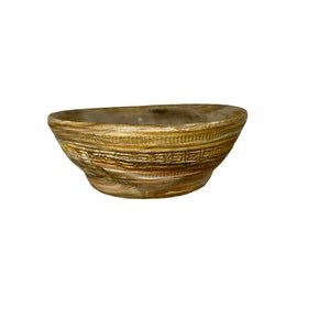 May include: A small, brown ceramic bowl with a decorative pattern around the rim. The bowl has a slightly marbled appearance.