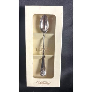 May include: A silver Lenox Williamsburg spoon in a cream box. The spoon features a long, slender handle and a decorative end with a floral design. The box displays the Lenox and Williamsburg logos.