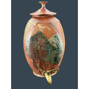 以下が含まれることがあります： 蓋と真鍮製の蛇口が付いたセラミック製のウォーターディスペンサー。 楕円形のディスペンサーは、テクスチャ加工された赤茶色の仕上げです。 緑と茶色のトーンの木と山のある風景が前面に描かれています。