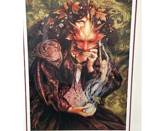 May include: A framed print titled "The Wild Wood" featuring a fantasy illustration. The artwork depicts a figure holding a red mask, with a mystical aura and a small, ethereal figure. The color palette includes shades of red, brown, and green.