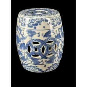 Puede incluir: Un taburete de jardín de cerámica azul y blanco con un diseño chino tradicional. El taburete tiene una parte superior redonda y una base cilíndrica con diseños recortados.