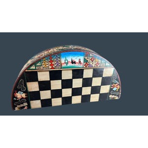 May include: Hand-painted wooden chess set with a unique, curved design. The chessboard features alternating black and white squares. The top edge is decorated with colorful Southwestern-style art, including desert landscapes and geometric patterns.