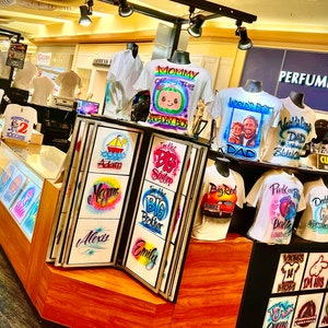 May include: A white ceramic mug with a black handle and the text "But First, Coffee" in a bold, black font. The mug is set against a neutral background, highlighting its simple design.