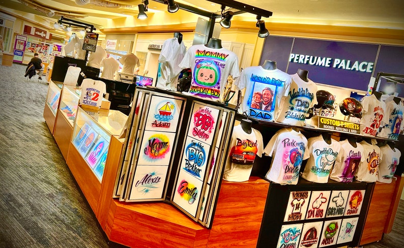 May include: A white ceramic mug with a black handle and the text "But First, Coffee" in a bold, black font. The mug is set against a neutral background, highlighting its simple design.