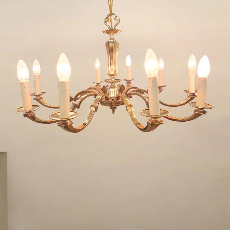 May include: A gold-toned chandelier with eight candle-style light bulbs. The chandelier has a decorative, ornate design with curved arms.
