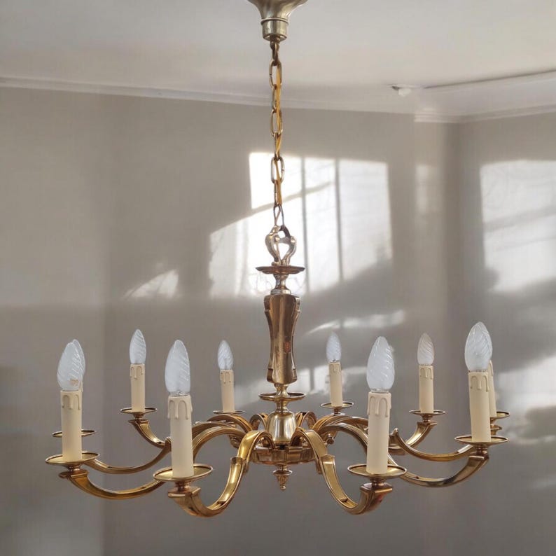 May include: A gold-toned eight-light chandelier with a decorative, ornate design. The chandelier has a chain and a central, decorative finial.